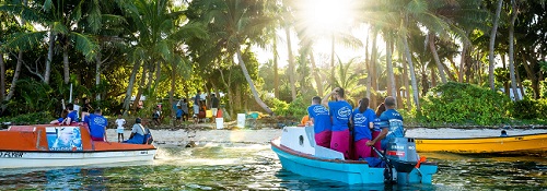 colourful boats carrying people arriving on a tropical island.